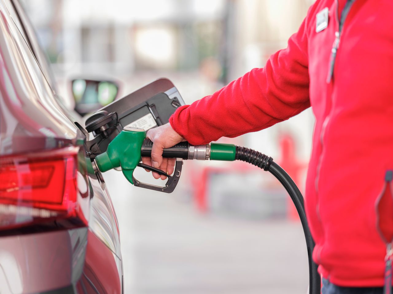 Offerings Close-up of a person refueling a car with a green hose at a gas station.