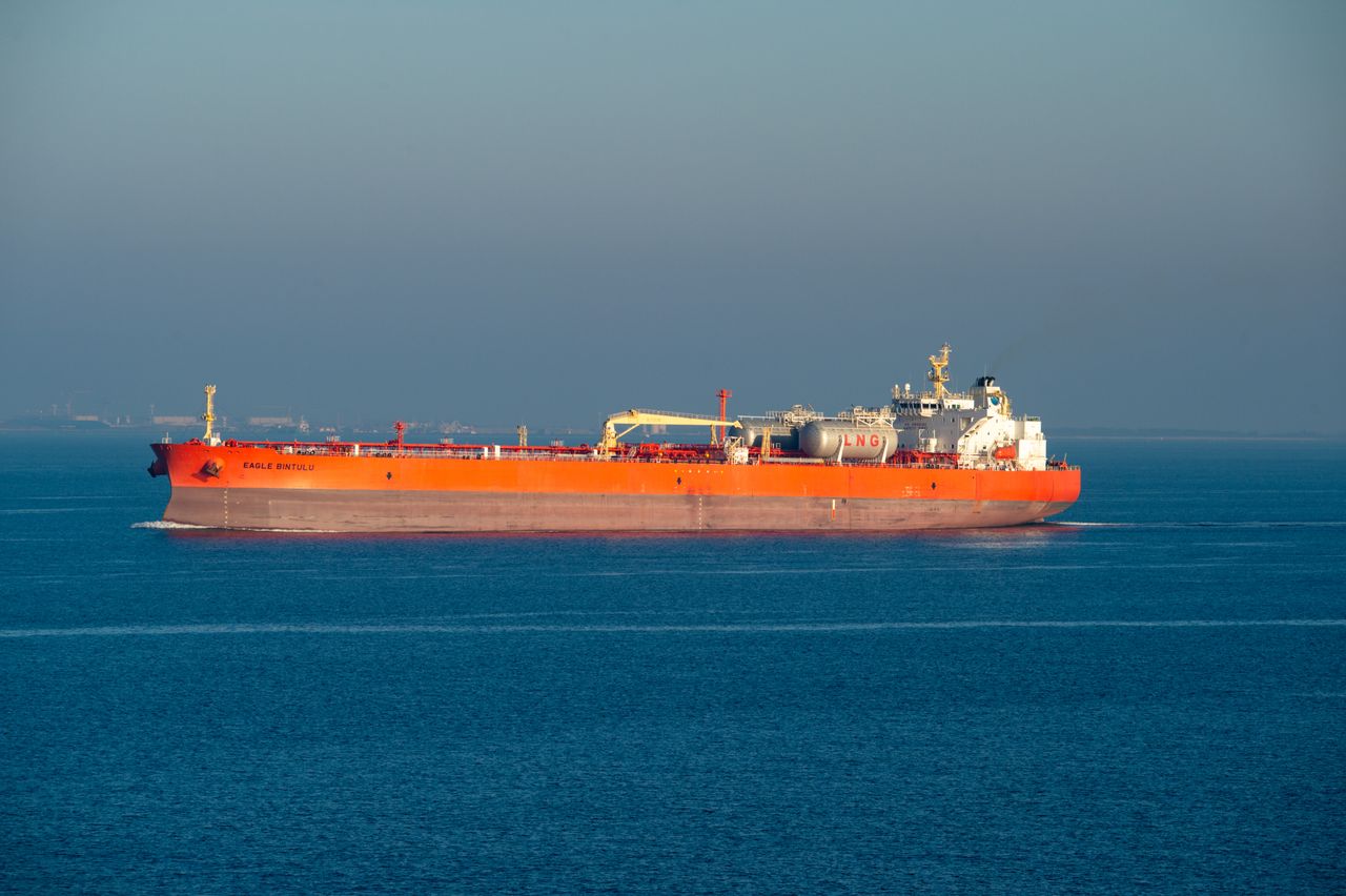 Offerings Bright orange LNG carrier ship cruising through calm sea waters on a clear day.